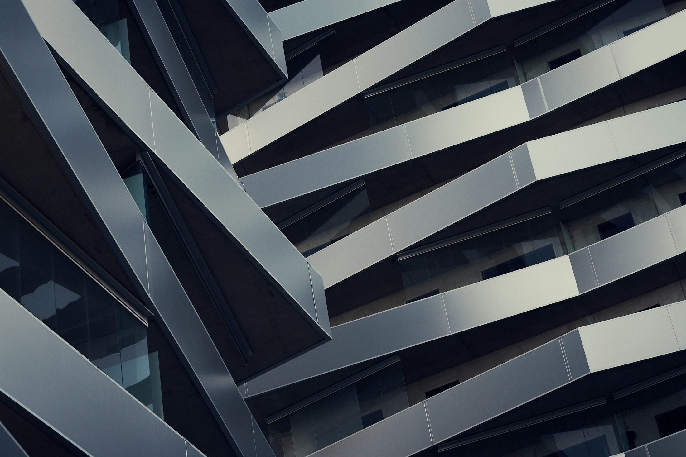 Interlocking steel and glass planes on a building facade, each one bearing on the next.