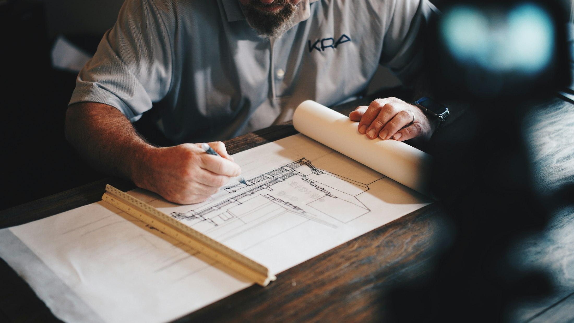 Hands working over technical drawings on a workbench, in an operating business.